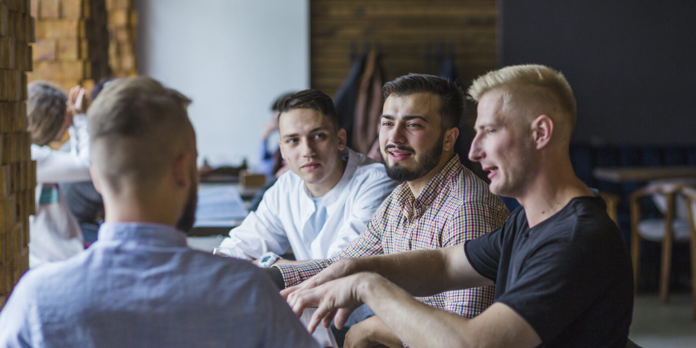 young-man-sitting-restaurant-explaining-strategy-his-friends